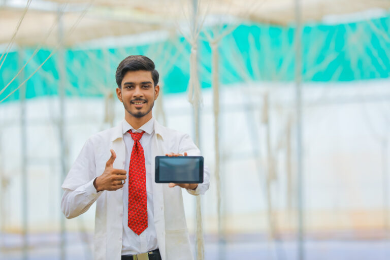 Technology and people concept, Young indian agronomist showing tablet or smartphone at greenhouse