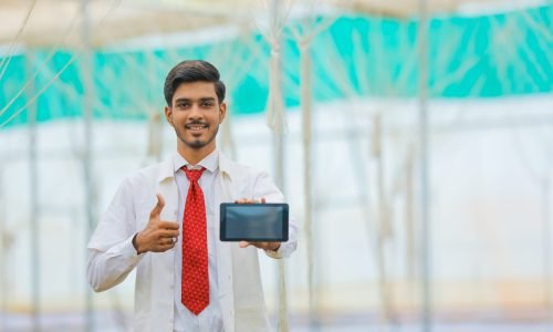 Technology and people concept, Young indian agronomist showing tablet or smartphone at greenhouse