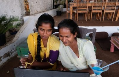 A high angle shot of two young Indian female friends enjoying their time in a cafe watching something on a laptop computer
